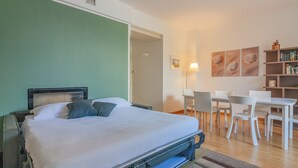 Un dormitorio con cama, mesitas de noche, un escritorio, sillas y una estantería.