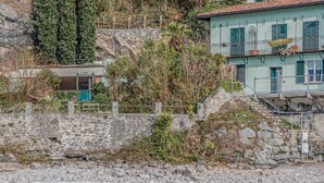 Un muro de piedra con una escalera que sube a un edificio con balcón.