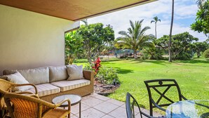 A covered patio area with a sofa, wicker chairs, and a small table.