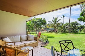 A covered patio area with a sofa, wicker chairs, and a small table.