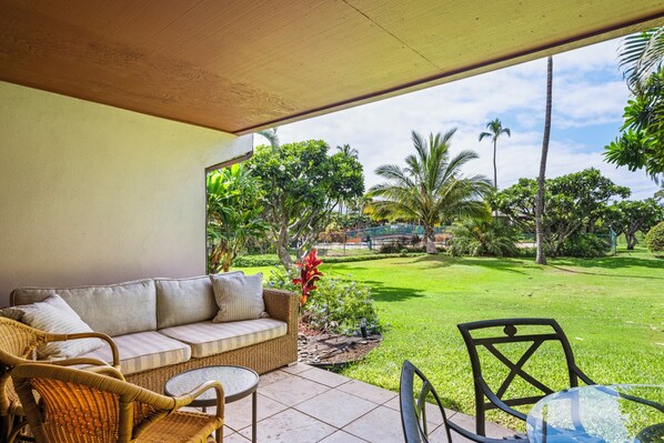 A covered patio area with a sofa, wicker chairs, and a small table. - Koa Resort 1B: Garden View Condo w/ AC, Shared Hot Tub & Pool (Kihei)