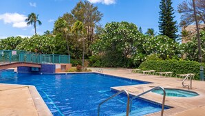A swimming pool with a bridge, surrounded by lush greenery and palm trees.