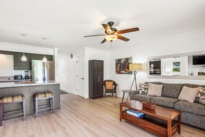 A modern living room with a sofa, coffee table, and a dining area with bar stools.