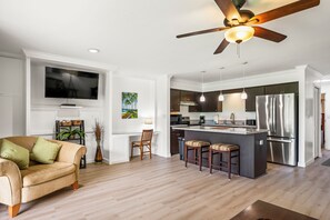 A modern kitchen with a central island, stainless steel appliances, and a ceiling fan.