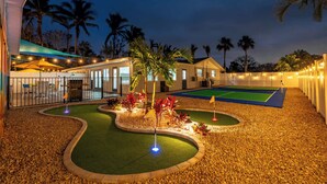 A well-lit mini-golf course with a netted area and palm trees in the background. - Pickleball, Game Room, Heated Pool, 4 Min to Beach (Bradenton)