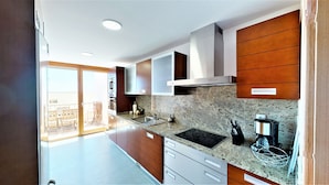 A modern kitchen with granite countertops, stainless steel appliances, and wooden cabinetry. - Lomas de los Monteros - Apartment with seaviews (Marbella)