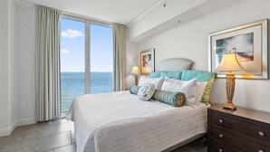 Ein Schlafzimmer mit einem großen Bett, einem Schminktisch, einer Lampe und einem gerahmten Bild an der Wand.
