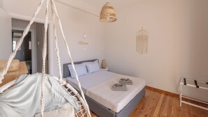 A bedroom with a bed, a hanging chair, a hanging light, and a wall decoration.