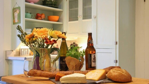 A kitchen counter with food items, a bottle, and a vase with flowers.