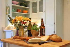 A kitchen counter with food items, a bottle, and a vase with flowers.