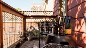 Une terrasse en bois avec une table-gril en métal, une chaise en métal et deux bouteilles de cidre de Sonoma posées sur un jardinière.