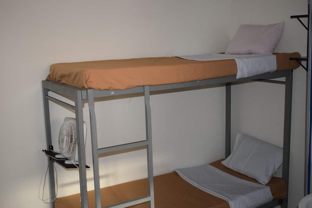 A bunk bed with a fan on the lower bunk.
