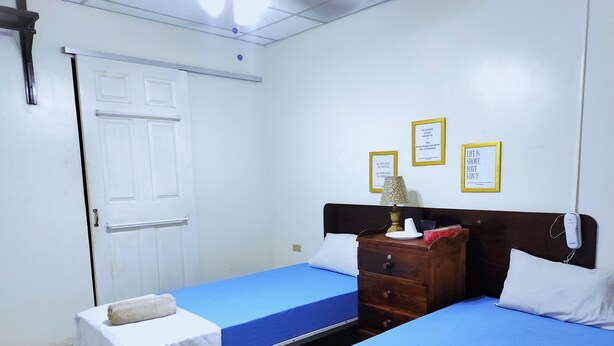 A hotel room with two beds, a wooden dresser, and a door. - Orison Managua (Managua)