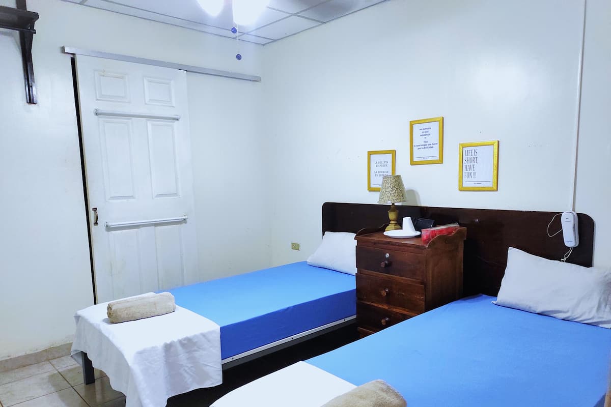 A hotel room with two beds, a wooden dresser, and a door.