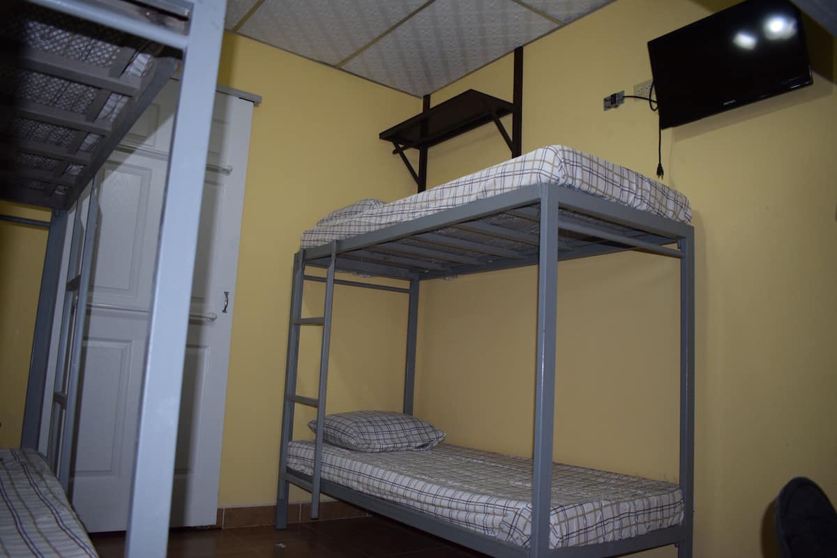 A bunk bed room with a television mounted on the wall.