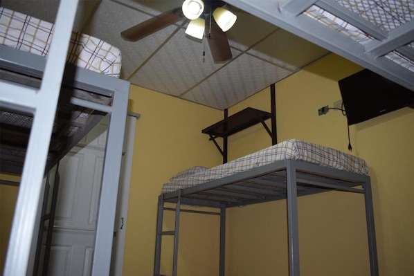 A dormitory room with bunk beds, a ceiling fan, and a window with a curtain. - Orison Managua (Managua)