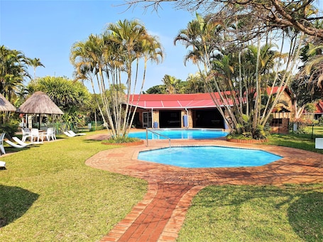 Una piscina al aire libre, sillones reclinables de piscina