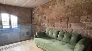 A room with a stone wall, a green sofa, and a window with a view. - Coventry Historic Houses (Coventry)