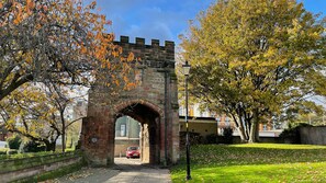 An arched stone gateway with a plaque, surrounded by trees and a clear sky. - Coventry Historic Houses (Coventry)