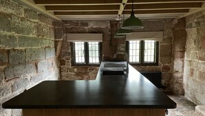 A kitchen with a long counter, wooden cabinets, and a window with a view. - Coventry Historic Houses (Coventry)