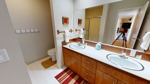 Een moderne badkamer met een dubbele wastafel, een houten wastafelmeubel en een grote spiegel.