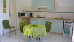 A small kitchen with a dining table, chairs, a microwave, a coffee maker, and cabinets.