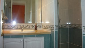 A bathroom with a sink, mirror, and shower.
