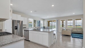 A modern kitchen with white cabinetry, stainless steel appliances, and a granite countertop. - Harry Themed-room, Spacious and Luxurious Villa #6st560 (Davenport)