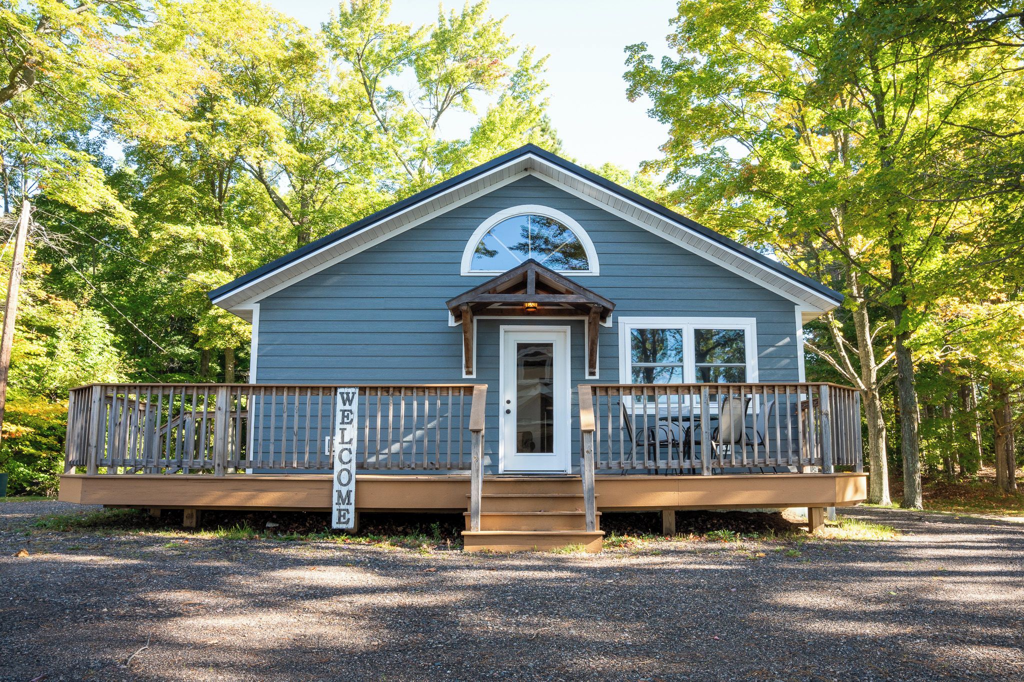A small cabin with a porch, a welcome sign, and a covered entryway.