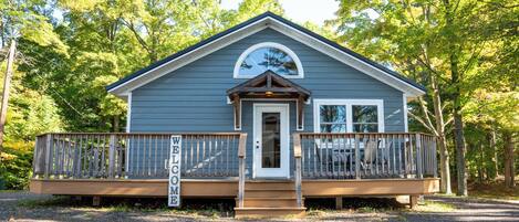 A small cabin with a porch, a welcome sign, and a covered entryway.