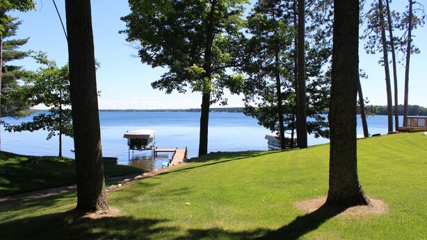 A lakeside view with a dock, grassy area, and trees. -  Lake Metonga Cabin (Crandon)