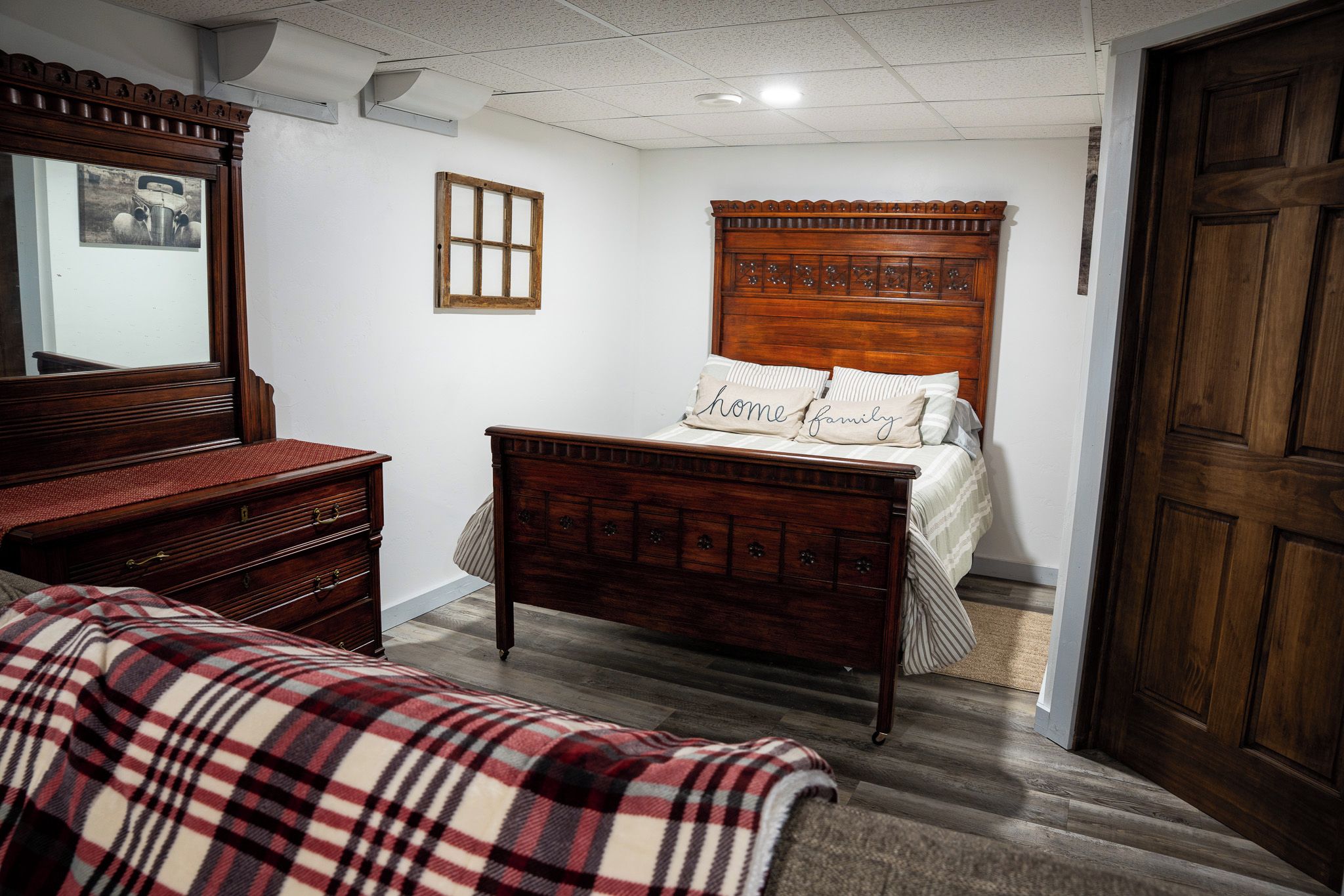 Une chambre à coucher avec un lit en bois, une commode, un miroir et une porte.