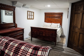Un dormitorio con una cama de madera, un tocador, un espejo y una puerta.