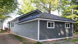 A two-story house with a grey exterior and white trim, number 107, 3, and a small porch area. -  Lake Metonga Cabin (Crandon)