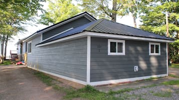 A two-story house with a grey exterior and white trim, number 107, 3, and a small porch area.