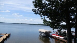 A calm lake with a dock, a covered boat, and a small boat. -  Lake Metonga Cabin (Crandon)