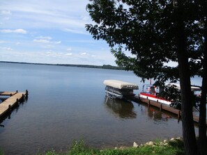 Un lac paisible avec un quai, un bateau à couvert et un petit bateau.