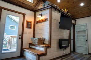 A wooden interior with a welcome sign, a wall-mounted TV, and a basket on a shelf.