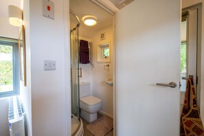 Une salle de bain avec des toilettes, une fenêtre et une douche.