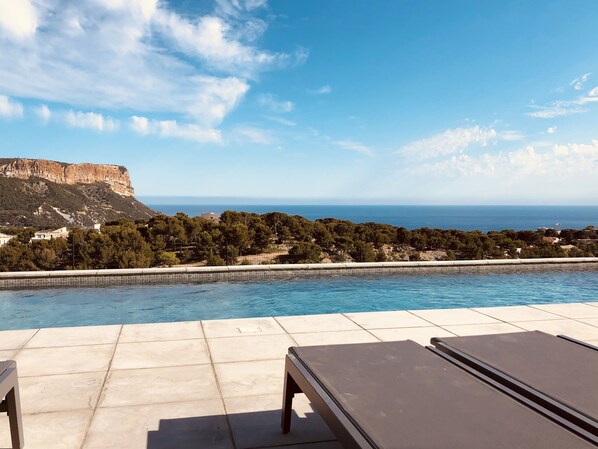 An infinity pool with a view of the sea and a mountain.