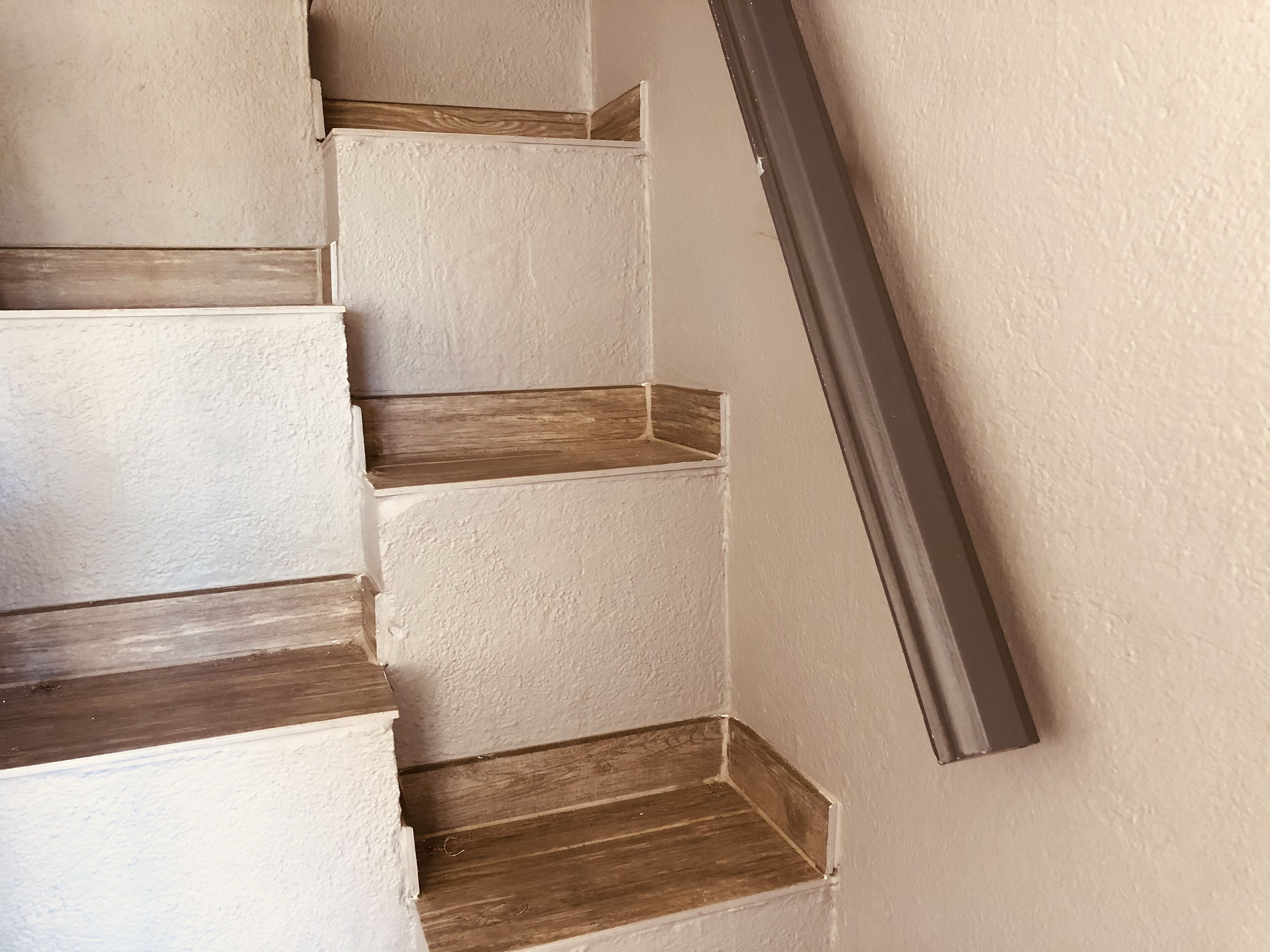 Una escalera con peldaños de madera y paredes blancas.