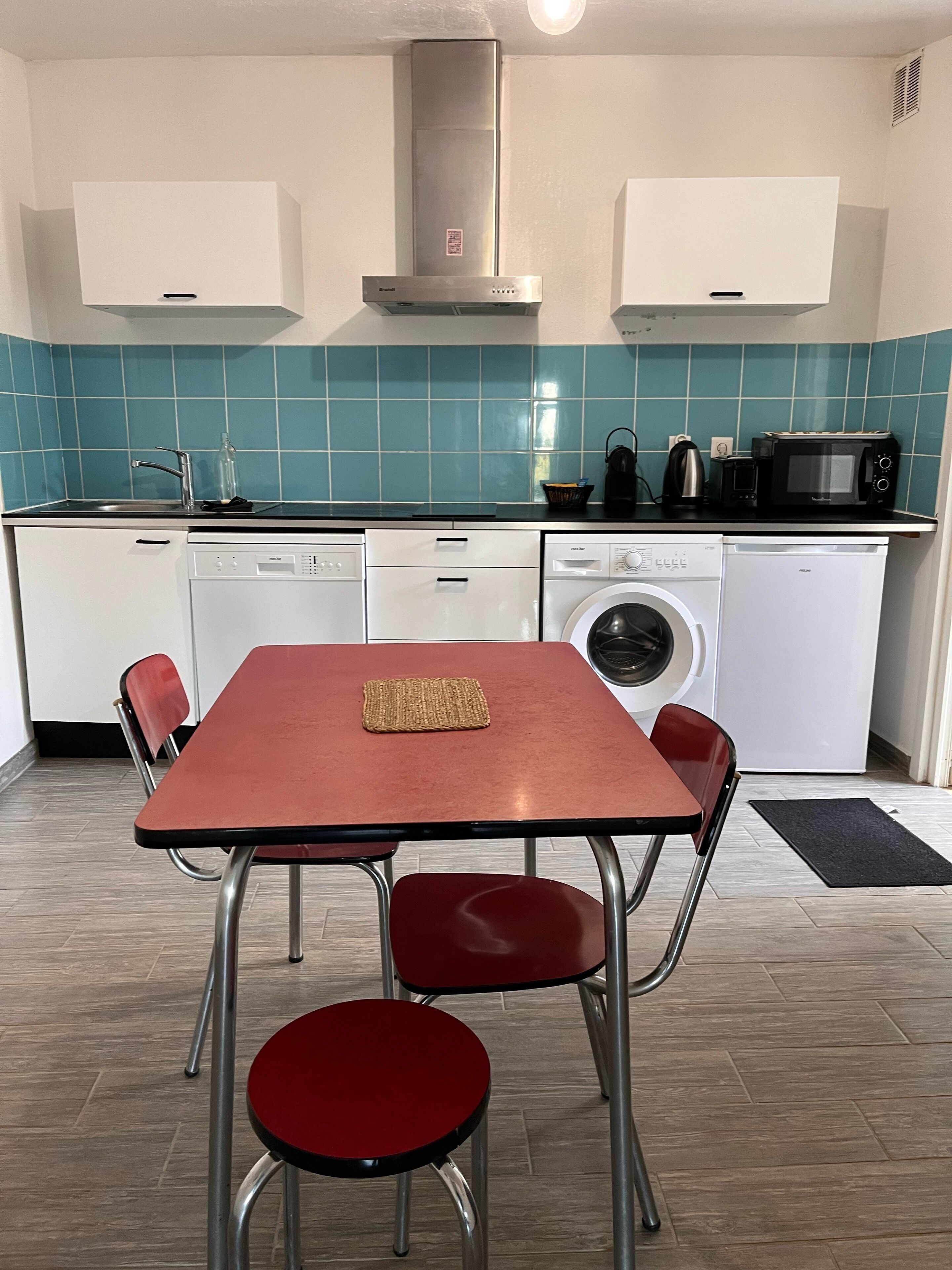 Une cuisine compacte avec un coin repas. Elle comprend un four à micro-ondes, un grille-pain et un lave-vaisselle.