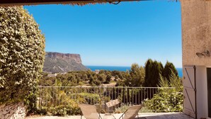 Un balcon donnant sur une falaise et la mer, un mur en pierre et un portail en métal.