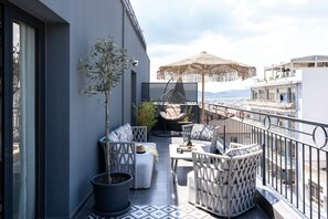 A balcony with wicker furniture, a potted plant, and a hanging chair.