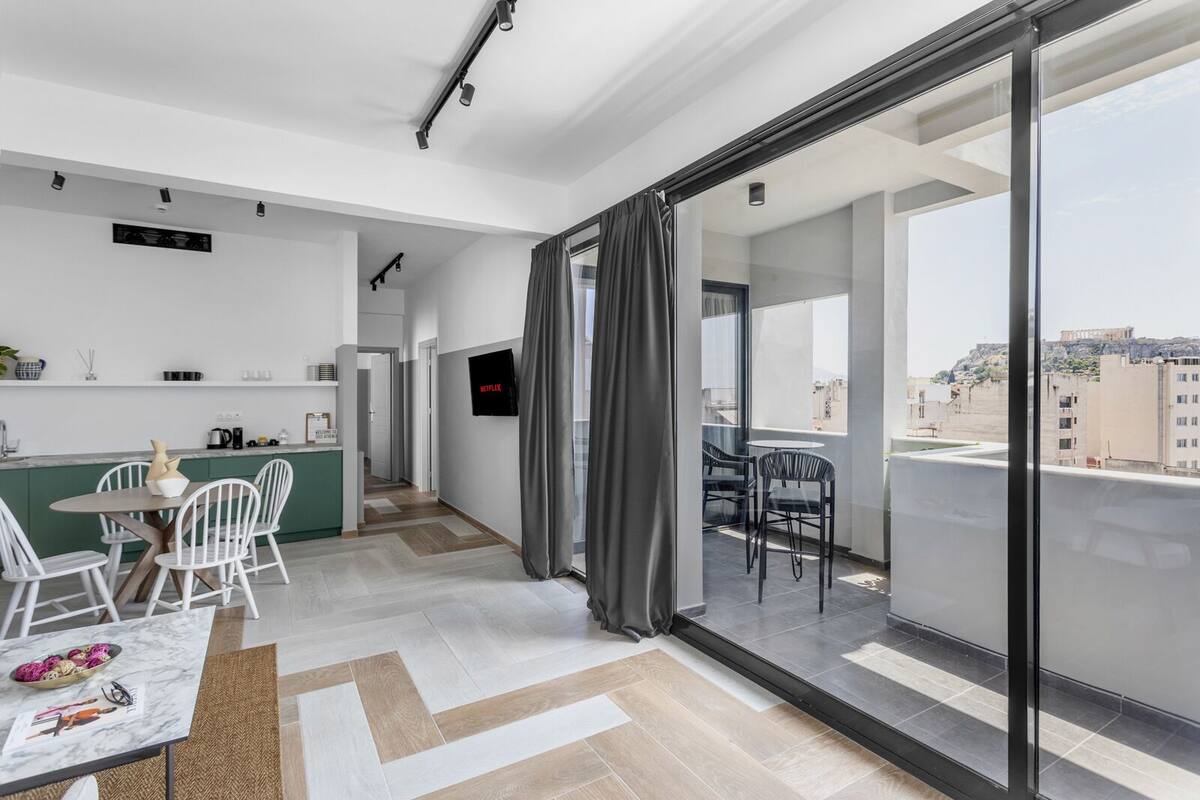 A modern apartment with a kitchen, dining area, and balcony with a city view.