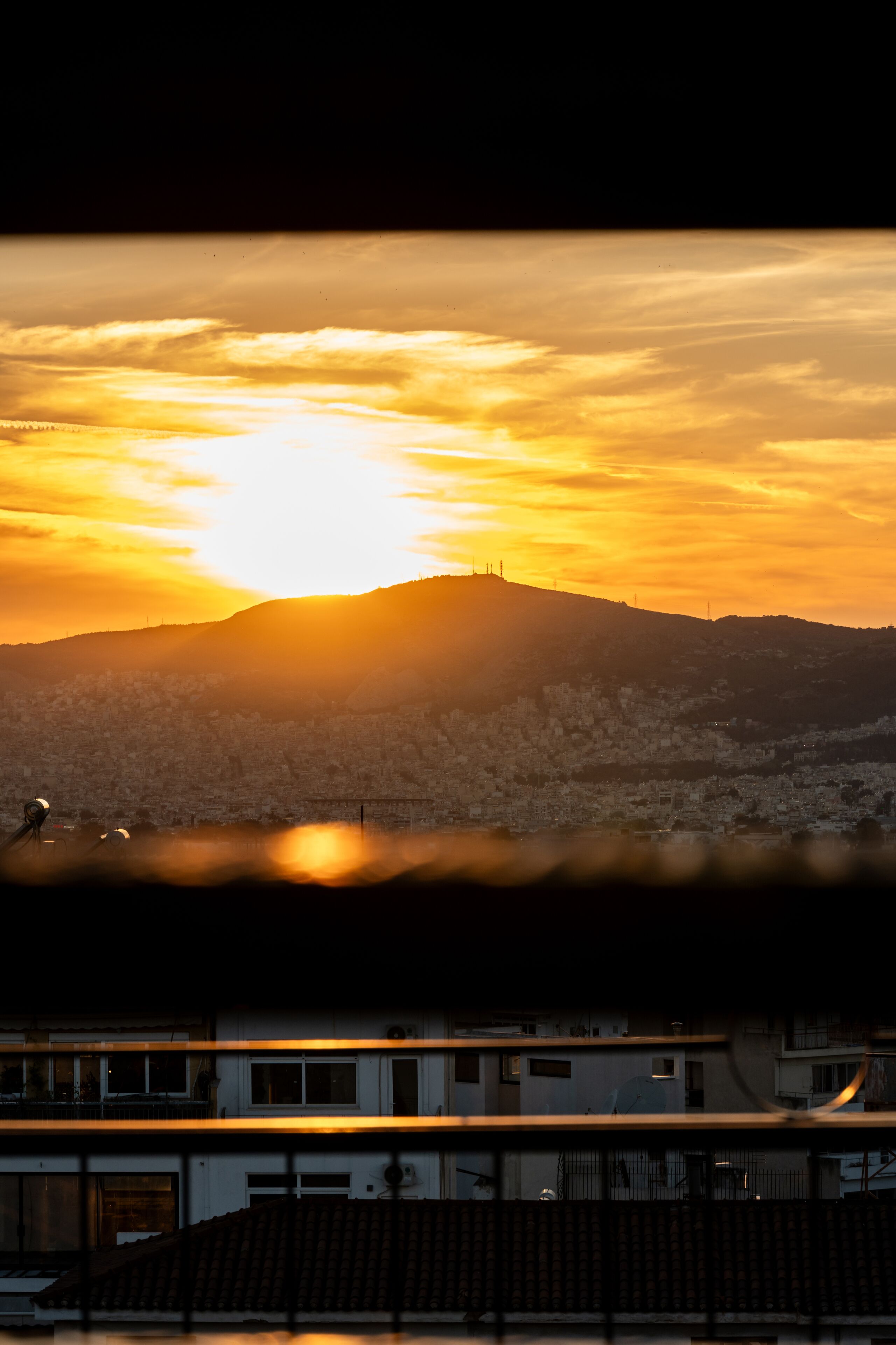 A sunset over a cityscape with a prominent hill.