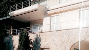 Ein zweistöckiges Gebäude mit einer Stein-Fassade, einem Balkon und einer Tür mit einem Schild.
