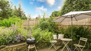 A patio with a grill, outdoor seating, and a wooden fence. - Old Schoolhouse (Aberfeldy)