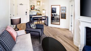 A modern living room with a sofa, armchair, and a dining area with a table and chairs.
