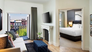 A hotel room with a balcony, a flat-screen TV, a fireplace, a bed, and a sofa.
